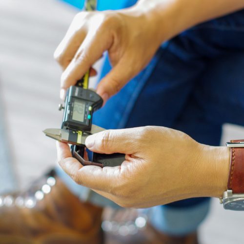 Hands using a digital caliper to measure a part