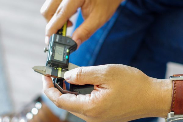 Hands using a digital caliper to measure a part