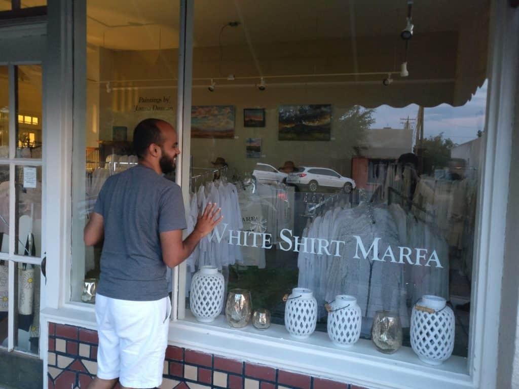 Deepak looking through a store selling white shirts